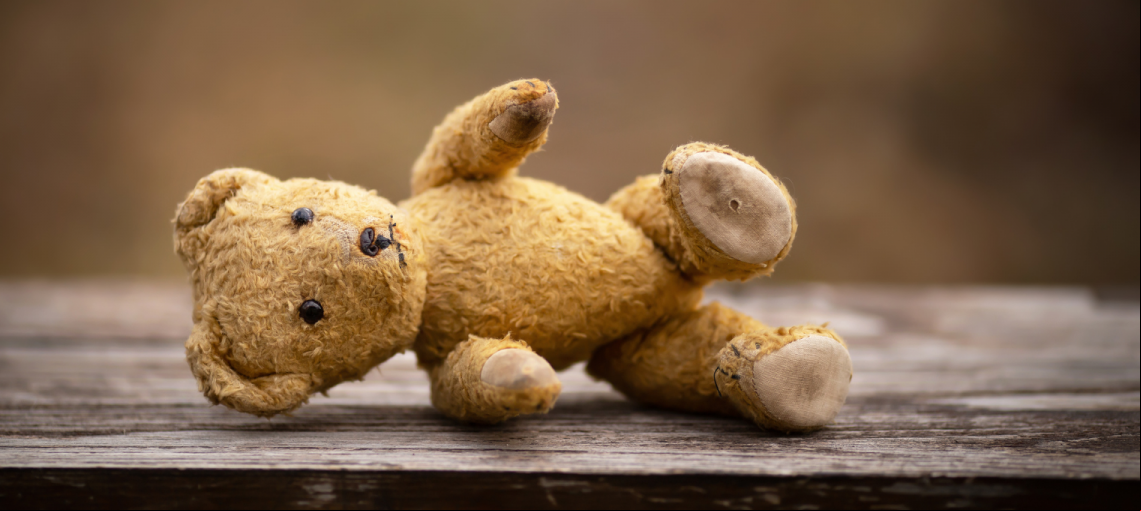 Foto de um urso de pelúcia caído no chão